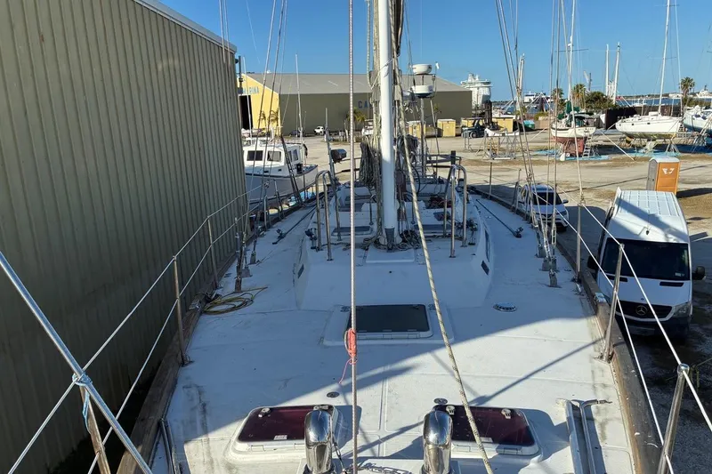 Slide: The Image of Sailboat Tayana 55, 1998 model, docked in a marina with surrounding boats and vehicles. - 6