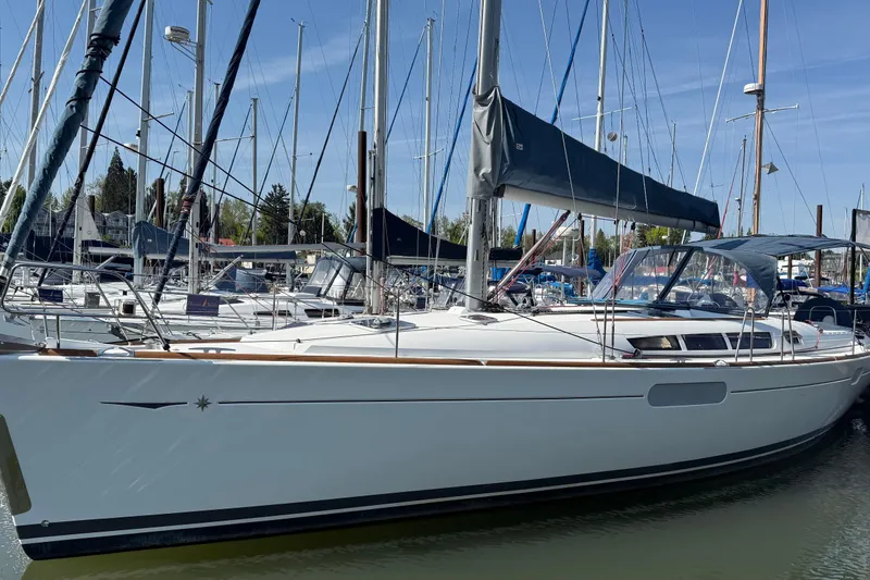 The Image of 2010 Jeanneau Sun Odyssey 44i sailboat docked in a marina, surrounded by other vessels. - 0