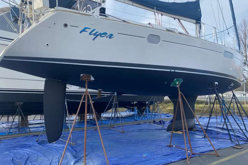 Slide: The Image of 2010 Jeanneau Sun Odyssey 44i sailboat on stands, named "Flyer," in a boatyard. - 37