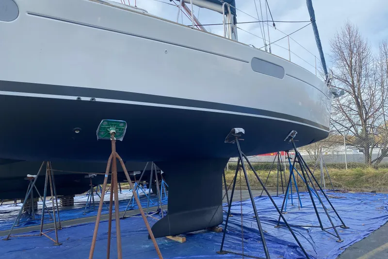 Slide: The Image of 2010 Jeanneau Sun Odyssey 44i sailboat on stands, hull view, outdoor setting. - 38