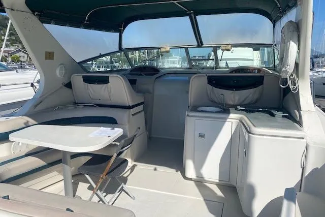 Slide: The Image of 1995 Regal 402 boat interior with seating, table, and helm in a marina setting. - 1