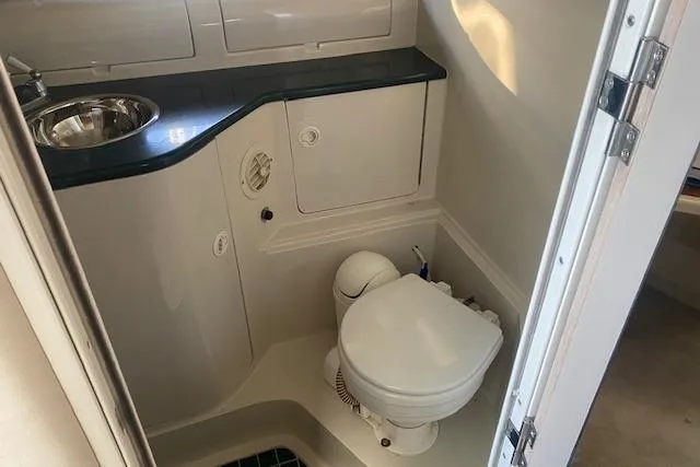 Slide: The Image of Compact bathroom in a 1995 Regal 402 boat, featuring a toilet and sink. - 12