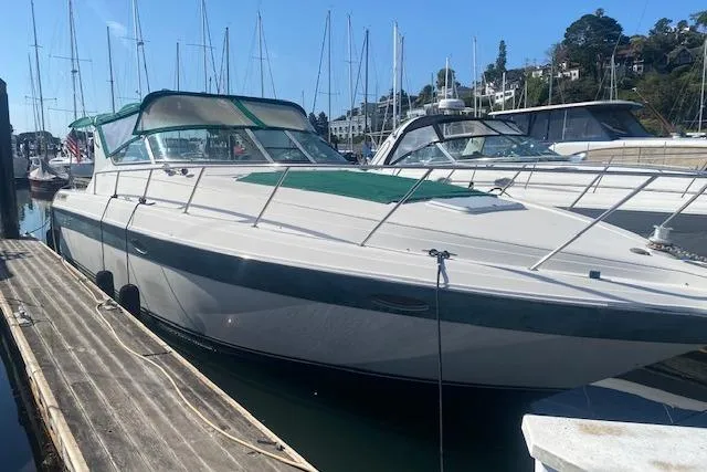 Slide: The Image of 1995 Regal 402 boat docked at marina with green canopy and sleek design. - 2