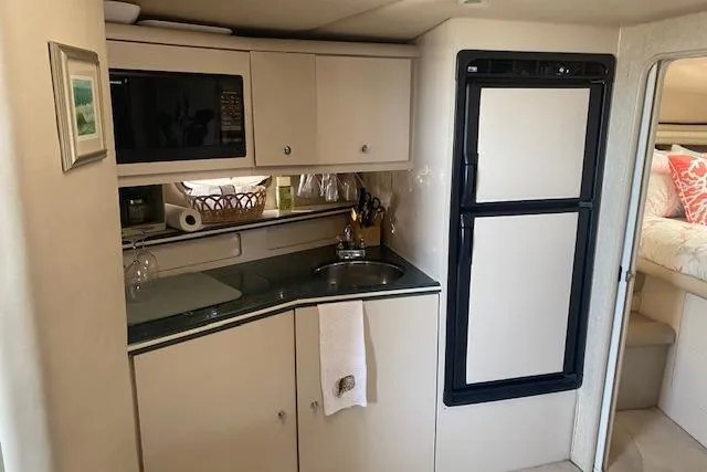 Slide: The Image of Compact kitchen area in a 1995 Regal 402 boat with sink, microwave, and fridge. - 8