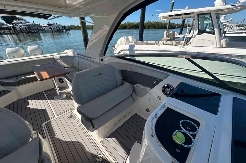 Slide: The Image of 2020 Sea Ray SLX 350 Outboard interior with seating and table, docked by the water. - 20