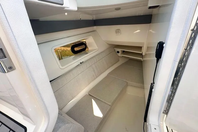 Slide: The Image of 2020 Sea Ray SLX 350 Outboard cabin interior with cushioned seating and window. - 25