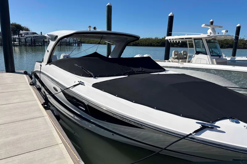 Slide: The Image of 2020 Sea Ray SLX 350 Outboard boat docked, covered, with clear blue sky background. - 29