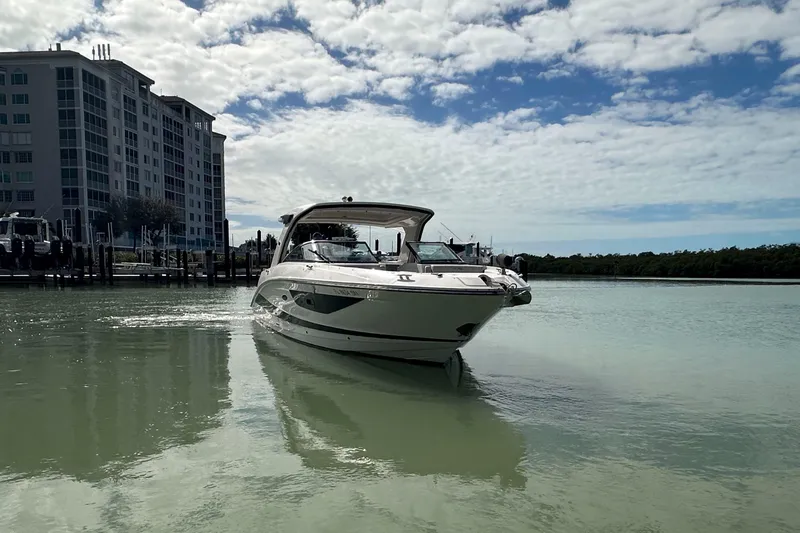Slide: The Image of 2020 Sea Ray SLX 350 Outboard cruising near a waterfront building under a partly cloudy sky. - 7