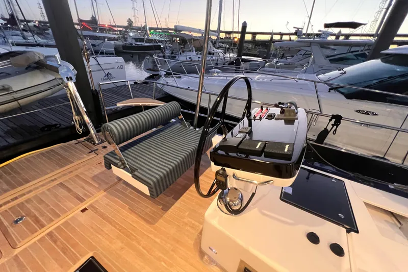 Slide: The Image of 2024 Hylas H57 yacht helm with striped seating, docked at marina during sunset. - 44