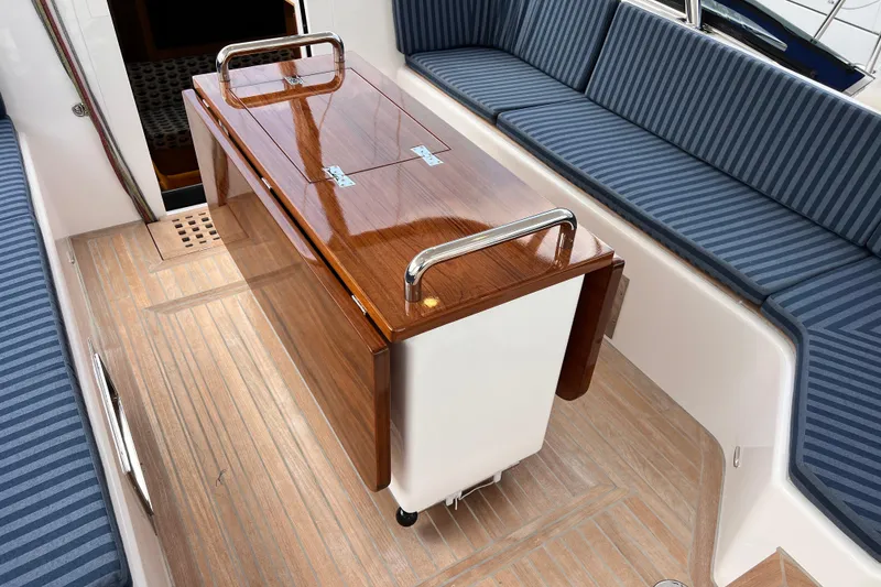 Slide: The Image of 2024 Hylas H57 yacht interior with wooden table and striped seating. - 62