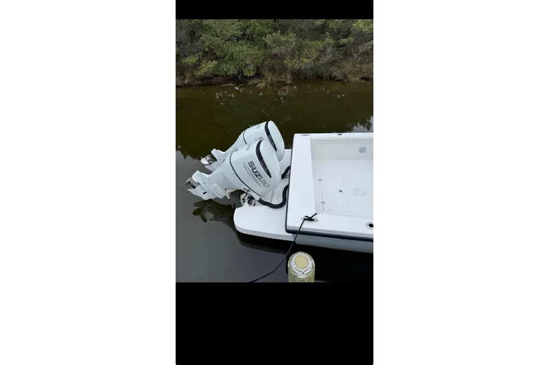 Slide: The Image of Ocean Master 27 boat with Suzuki outboard motor, docked in calm waters, 2021 model. - 4