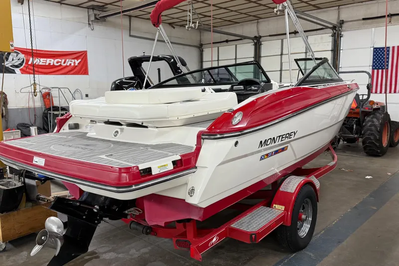 The Image of 2014 Monterey 214SS Super Sport boat on trailer in garage, red and white design. - 1