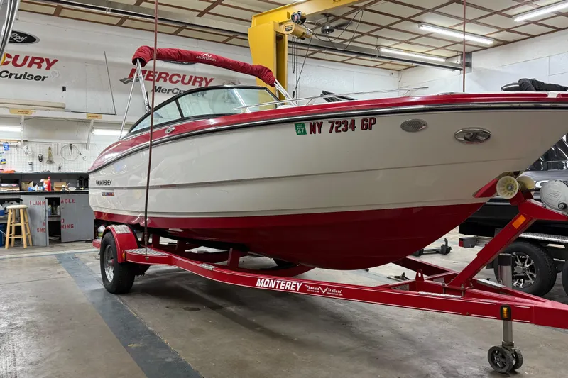 Slide: The Image of 2014 Monterey 214SS Super Sport boat on red trailer in a workshop. - 2