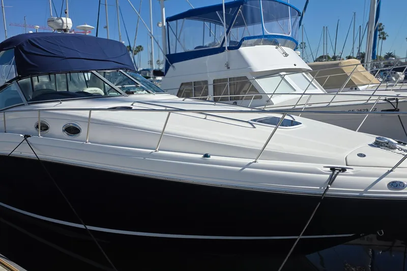 Slide: The Image of 2005 Sea Ray 340 Sundancer yacht docked at marina, featuring sleek design and blue canopy. - 2