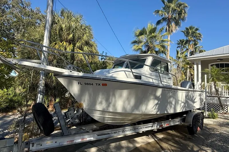 The Image of 2020 Parker 2320 SL Sport Cabin boat on trailer, surrounded by palm trees. - 0