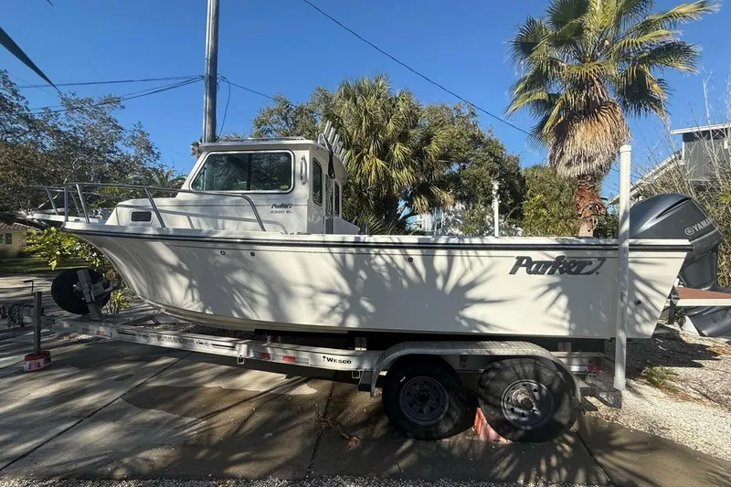 Slide: The Image of 2020 Parker 2320 SL Sport Cabin boat on trailer, parked outdoors with palm trees. - 1