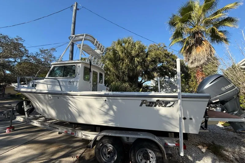Slide: The Image of 2020 Parker 2320 SL Sport Cabin boat on trailer, surrounded by palm trees. - 48