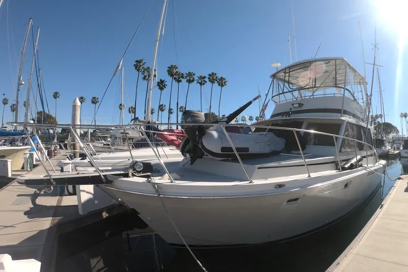 The Image of 1984 Uniflite 38 Convertible yacht docked at marina under clear blue sky. - 0