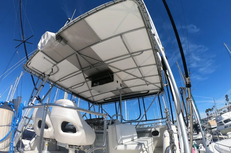 Slide: The Image of 1984 Uniflite 38 Convertible boat with canopy and seating, docked under clear blue sky. - 11
