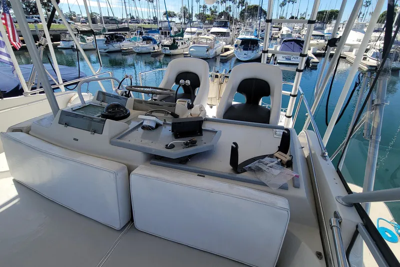Slide: The Image of 1984 Uniflite 38 Convertible boat helm with marina view, featuring navigation equipment and seating. - 13
