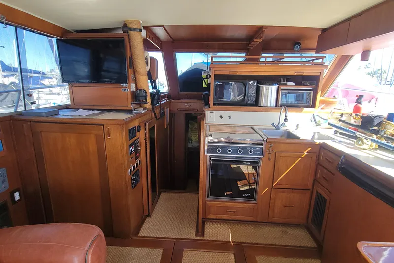 Slide: The Image of 1984 Uniflite 38 Convertible yacht interior with kitchen, wooden cabinetry, and appliances. - 21