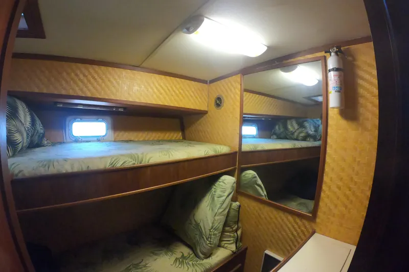 Slide: The Image of 1984 Uniflite 38 Convertible cabin with bunk beds, tropical decor, and a fire extinguisher. - 25