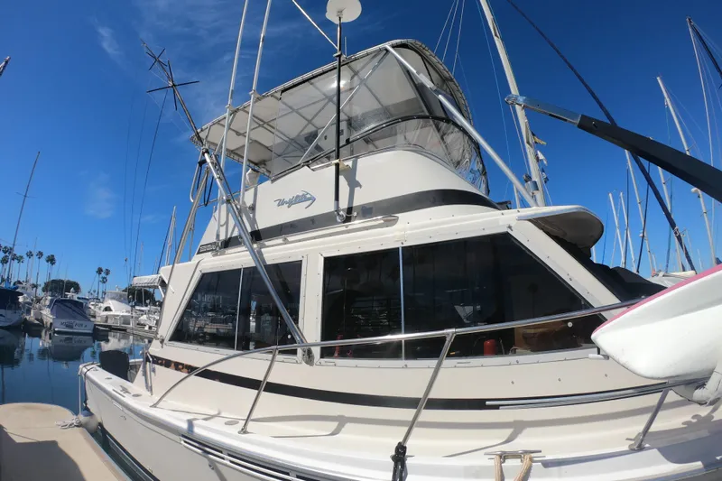 Slide: The Image of 1984 Uniflite 38 Convertible yacht docked in a marina under clear blue skies. - 4