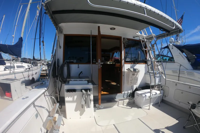 Slide: The Image of 1984 Uniflite 38 Convertible yacht docked, featuring a spacious deck and ladder access. - 6