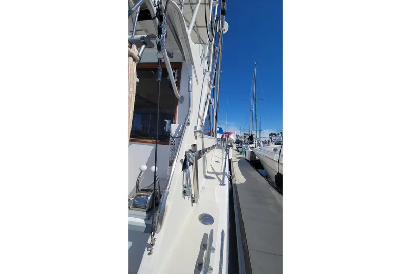 Slide: The Image of 1984 Uniflite 38 Convertible yacht docked, showcasing side view and rigging against clear blue sky. - 8