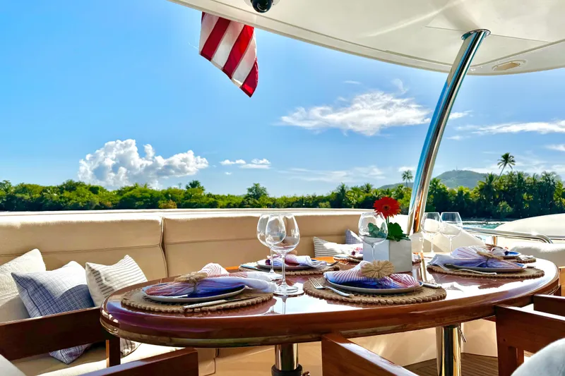 Slide: The Image of Luxurious Horizon E88 yacht dining area with elegant table setting, tropical backdrop, and American flag. - 74