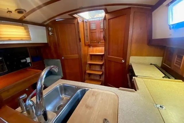Slide: The Image of Interior of a 1996 Gozard 31 boat, featuring a wooden kitchen and stairs. - 31