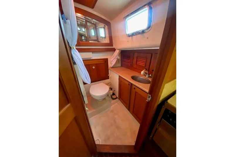 Slide: The Image of Bathroom interior of 1996 Gozard 31 boat with wooden cabinets and porthole window. - 32