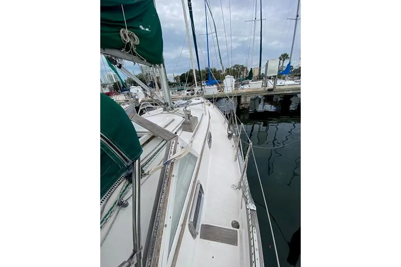 Slide: The Image of 1996 Gozard 31 sailboat docked at marina, featuring green sails and overcast sky. - 8