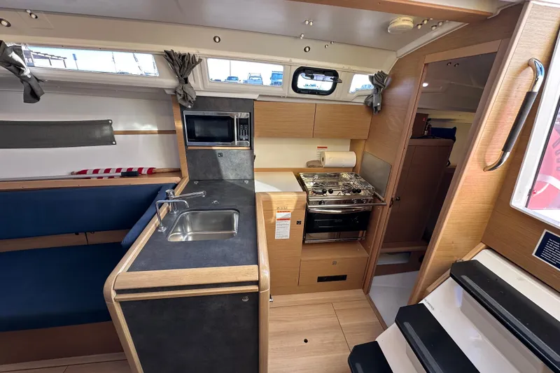 Slide: The Image of Interior of 2021 Jeanneau Sun Odyssey 349 sailboat, featuring a compact kitchen with sink and stove. - 36