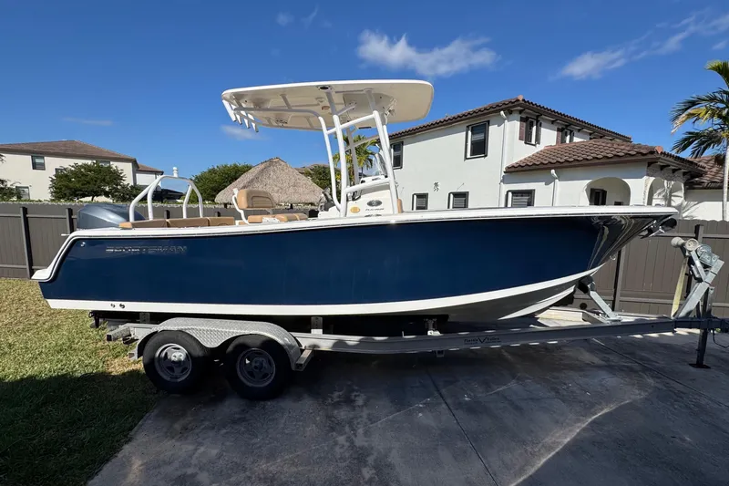 The Image of 2014 Sportsman Heritage 231 Center Console boat on trailer in residential driveway. - 0