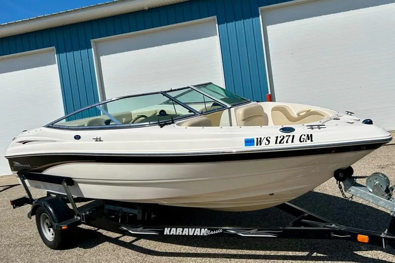 The Image of 2003 Chaparral 183 SS boat on Karavan trailer, parked outside blue building. - 0