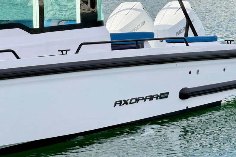 Slide: The Image of 2025 Axopar 37 XC Cross Cabin boat docked in a marina with sailboats. - 10