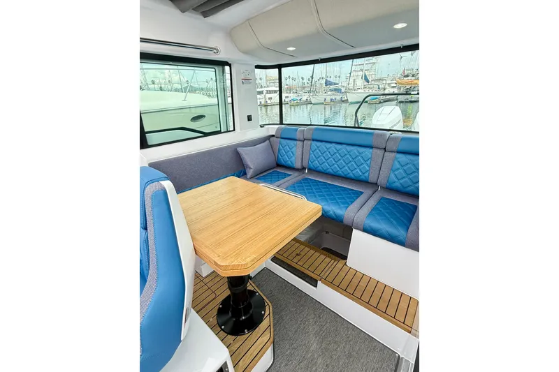Slide: The Image of 2025 Axopar 37 XC Cross Cabin interior with blue seating and wood flooring. - 15