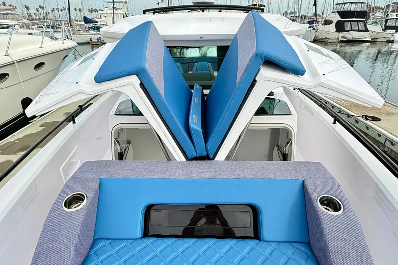 Slide: The Image of 2025 Axopar 37 XC Cross Cabin with blue seating, open hatches, and marina background. - 43
