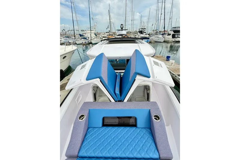 Slide: The Image of 2025 Axopar 37 XC Cross Cabin boat with blue seating, docked in a marina. - 44