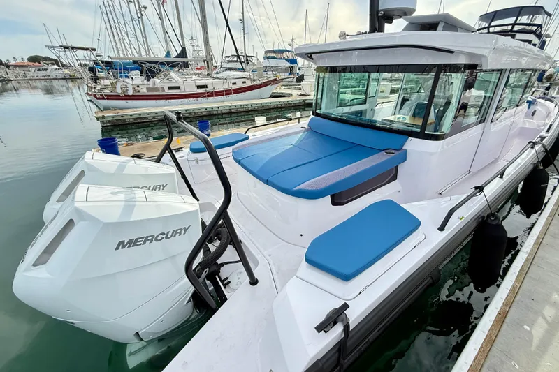 Slide: The Image of 2025 Axopar 37 XC Cross Cabin boat docked with Mercury engines, featuring blue seating. - 55