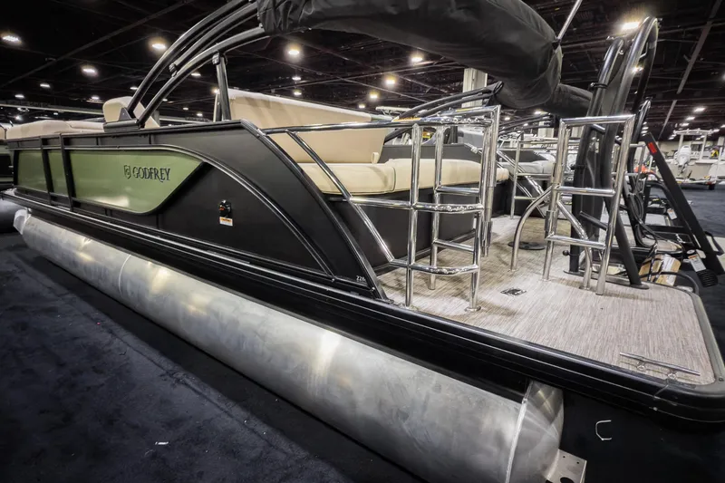 Slide: The Image of 2026 Godfrey Sweetwater 22' Tritoon boat with flip lounge, showcased indoors. - 2