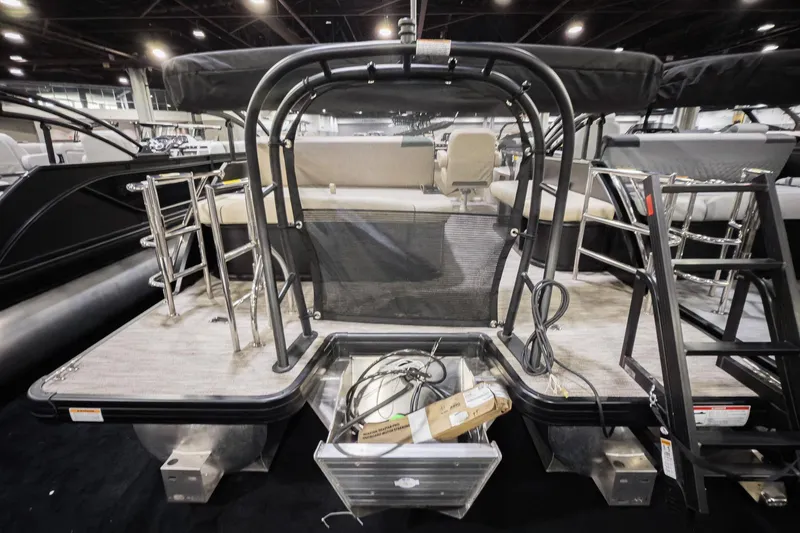 Slide: The Image of 2026 Godfrey Sweetwater 22' Tritoon boat with flip lounge and ladder, showcased indoors. - 3
