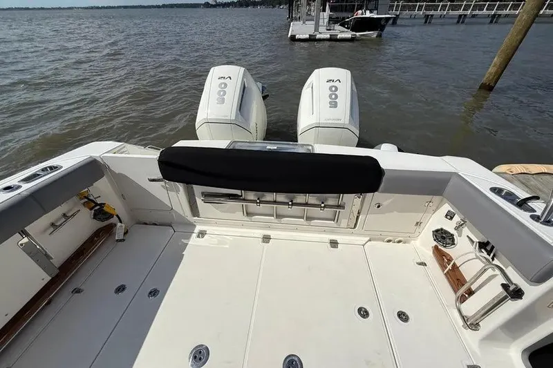 Slide: The Image of 2024 Boston Whaler 380 Outrage boat with dual outboard engines docked on a lake. - 22