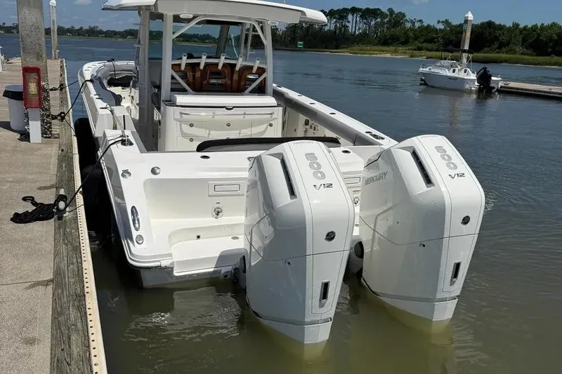 Slide: The Image of 2024 Boston Whaler 380 Outrage with dual Mercury V12 engines docked by the water. - 5
