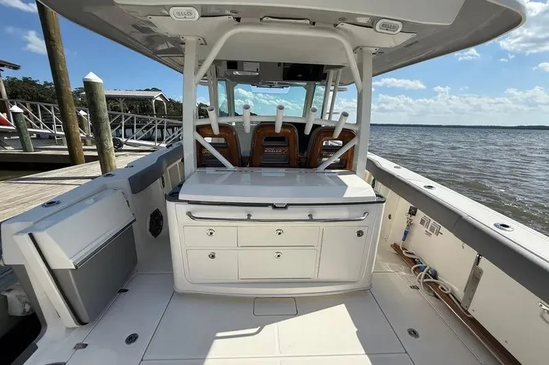 Slide: The Image of 2024 Boston Whaler 380 Outrage boat interior with seating and storage, docked by the water. - 8