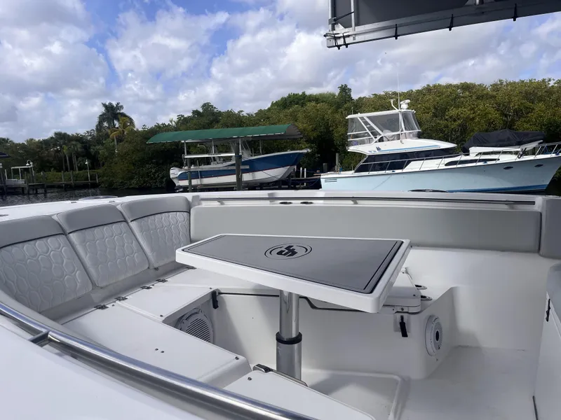 Slide: The Image of 2021 Sea Fox 368 Commander boat interior with seating and table, docked near other boats. - 22