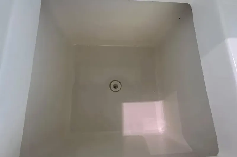 Slide: The Image of 2024 Pursuit S 358 Sport boat storage compartment, empty with a drain at the bottom. - 8