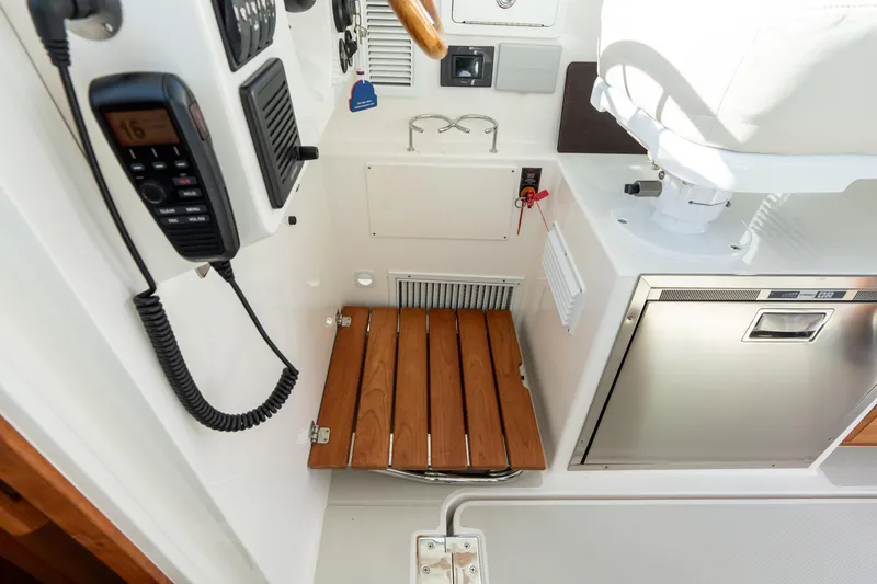 Slide: The Image of 2023 Back Cove 340 boat interior with wooden fold up step, control panel, and stainless steel appliance. - 33