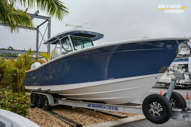 Slide: The Image of 2026 Blackfin 332 CC boat on trailer, displayed outdoors near palm trees. - 10